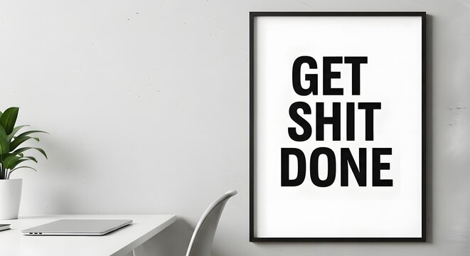 A modern minimalist workspace featuring a motivational poster with bold black text on a white background, a sleek white desk, a closed laptop, and a small potted plant in a bright room