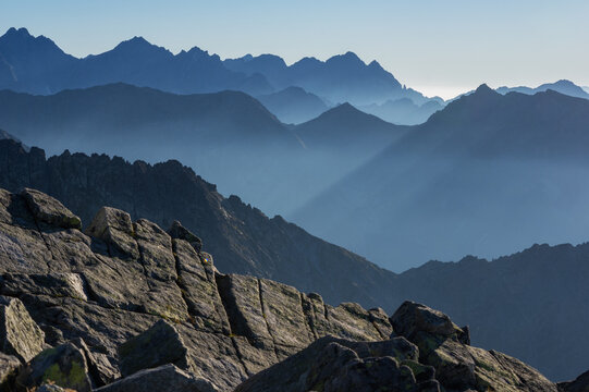Aerial view of jagged mountain peaks pierce the mist, a symphony of blue and grey under the crisp sky in Jahnaci stit, Vysoke Tatry, Presov Region, Slovakia. - Powered by Adobe