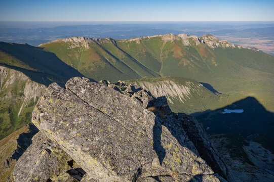 Aerial view of sun-kissed mountain peaks casting long shadows across rugged terrain, Jahnaci stit peak, Presov Region, Slovakia.