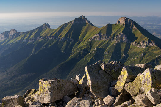 Aerial view of the rugged Jahnaci stit peak, where sunlight paints the sharp ridges in vibrant green and casts deep shadows into the valleys below, Vysoke Tatry, Presov Region, Slovakia.