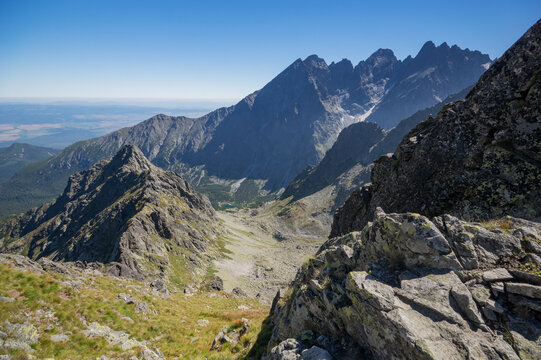 Aerial view of jagged peaks pierce the clear blue sky, casting long shadows across the rugged terrain of Jahnaci stit peak, Vysoke Tatry, Presov Region, Slovakia.