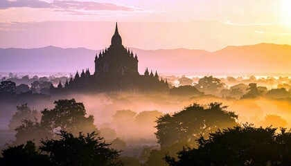 Fototapeta premium A silhouette of an ancient temple complex rises majestically from a sea of fog during a vibrant sunrise, with rolling hills in the background.
