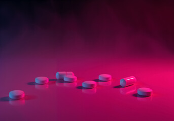 Dramatic Studio Shot of White Pills on Reflective Pink Surface
