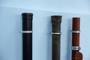 Various materials of vertical pipes mounted on a blue wall create an industrial aesthetic