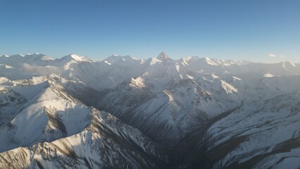 A breathtaking view of a snow-covered mountain range stretches across the horizon, showcasing dramatic peaks and valleys under a clear blue sky, highlighting the beauty of nature's landscape