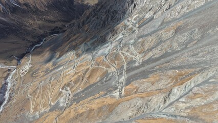 Captivating aerial perspective showcasing a winding road traversing rocky mountain terrain, surrounded by rugged landscapes and valleys, highlighting the natural beauty and adventure of the area