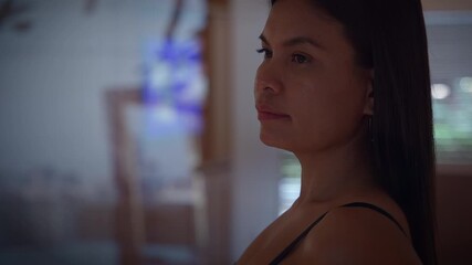 woman viewing television, woman watching screen thoughtfully, woman in subdued lighting observes tv