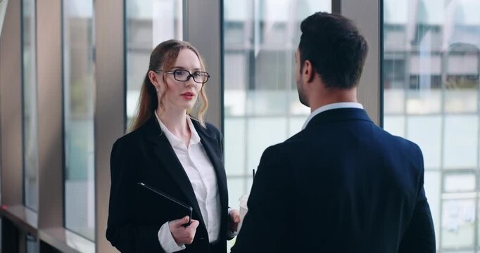 Two Office Colleagues Standing By The Window While Having a Conversation. - medium shot