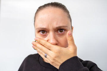 Young woman covers mouth with hand, Oops, too late, realizing she said something inappropriate, expression shock, human reaction regret, gossip slips out, awkward moment, communication mistake