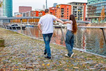 Happy young couple, happy girl and man together, shared journey, planning, waterfront promenade, modern apartment buildings, and considerations, intimate moment in urban landscape, cheerful dreams