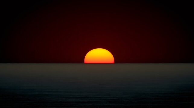 Red sun setting below the ocean surface with a dark red sky, reflecting on the tranquil water. Serene end of day