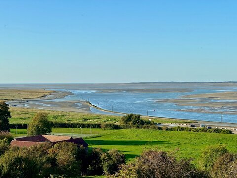 Cap Hornu panoramic vista across the Somme Bay at low tide from Saint-Valery-sur-Somme, showing winding tidal channels, broad sandbanks, marker buoys, seabirds and lush pastures beneath an autumn sky - Powered by Adobe