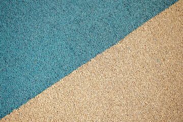 Granulated sports and playground surface in blue and beige colors, textured material pattern. Real photo © LariBat