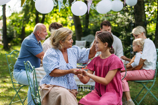 Grandmother talking with granddaughter at family garden party.