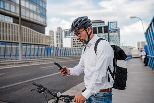 Manager on bike, reading text message on phone. - Powered by Adobe