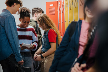 Teen students hanging out in school hallway by lockers.