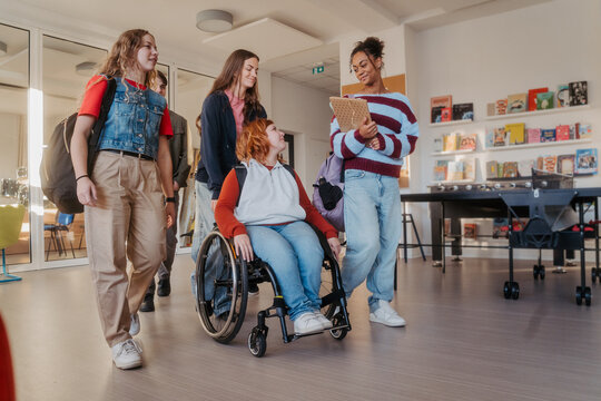 Teen students in school hallway, girl in wheelchair.