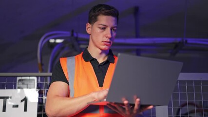 Electrician worker, serious and focused, operates a laptop within an industrial environment. Diligence and confidence are evident while performing vital digital tasks, showing quiet determination. - Powered by Adobe