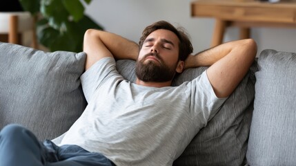 Man relaxing on a couch with hands behind his head in a cozy living room during the day