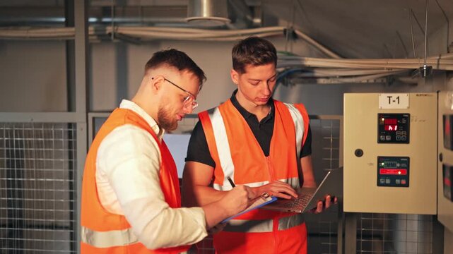 Industrial workers meticulously review data, documenting findings. Professionals ensure seamless system maintenance and operational integrity with focus and responsibility.