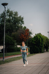Obraz premium Young sporty woman drinking water after running in the park