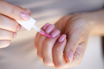 Applying bright pink nail polish during a home manicure while si