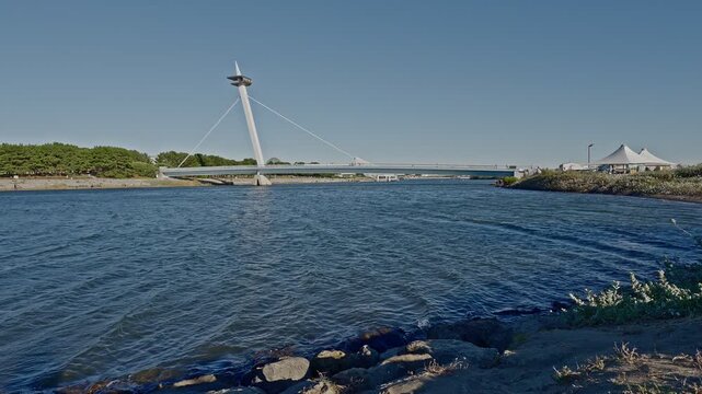 The iconic Kasai Nagisa Bridge, designed like a sailboat mast, connecting the West Beach to the city under a vast Tokyo sky.