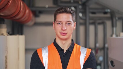 Young professional plumber with serious expression in protective vest ready for work. Represents dedication and skilled labor within engineering, construction, or maintenance.
