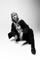 In a clean, minimal studio space, a young person strikes a confident pose