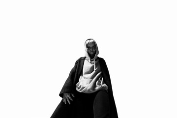 A person dressed in a cozy hoodie and a flowing cloak stands tall, exuding confidence. The simple background emphasizes their unique style and expression, inviting curiosity about their story