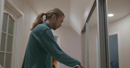 Man is Ironing Shirt at Home in Corridor. 4K 10-bit