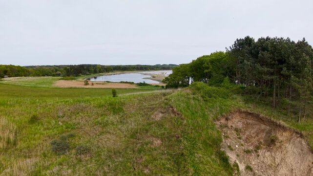 Drone footage overlooking rugged cliffs, pine trees, and a calm inlet within Denmark&rsquo;s Mols Bjerge National Park