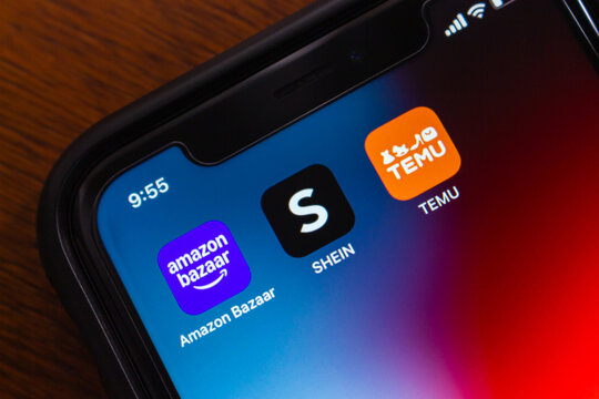 Quito, ECUADOR - Nov 11 2025 : Amazon Bazaar, SHEIN, and TEMU app icons are seen in an iPhone, representing popular online shopping and fashion platforms.