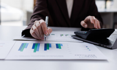 Professional calculator to check analyzing financial data graphs, charts on laptop display at a modern workspace. Financial analysis or business evaluation concept