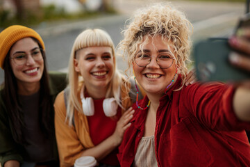 Happy friends taking selfie outdoors in city