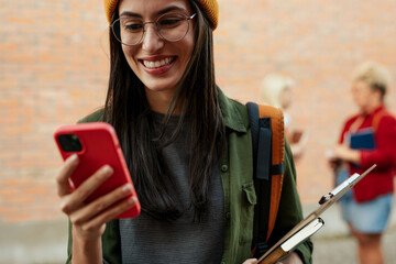 Young woman student smiling using smartphone on campus