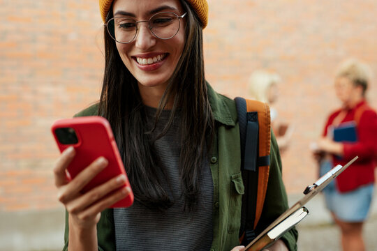 Young woman student smiling using smartphone on campus