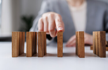 Problem Solving, Close up hand of business woman stopping falling blocks on table.
