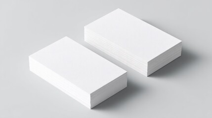 A minimalistic image showcasing two stacks of blank white business cards on a light background, emphasizing simplicity and elegance in design.