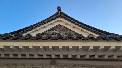traditional korean hanok roof gable with decorative tiles and blue sky