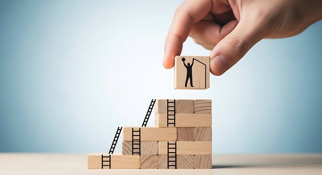 Hand stacking wooden blocks to build a staircase with a silhouette of a person celebrating success on top