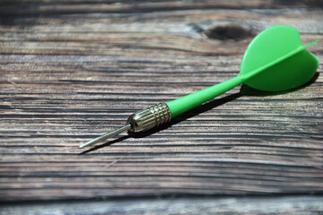 Green dart on wooden background. Business concept. Selective focus. Dart arrow on a table.