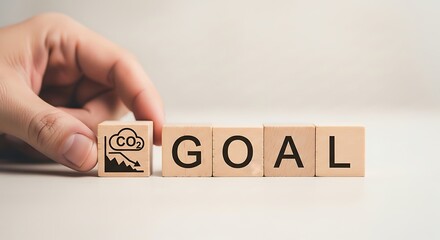 Hand placing a block with a co2 icon and mountain, spelling out the word goal on wooden blocks, representing environmental goals and carbon footprint reduction