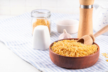 Raw uncooked orzo pasta, Italian dry pasta risoni orzo in bowl on table, copy space
