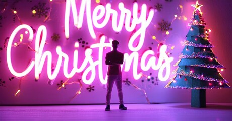 Bright neon sign displays holiday greeting. Person stands before festive Christmas tree, pink lighting dominates scene.