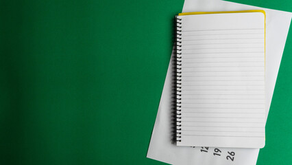 Blank notebook and a calendar Working table with keyboard and notepad, pen, pencil and plant in...