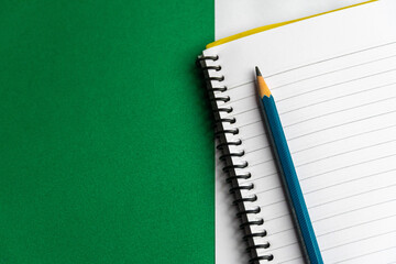 Blank notebook and a calendar Working table with keyboard and notepad, pen, pencil and plant in home office. top view 