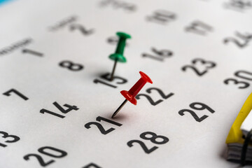 Push-pin in calendar with a blank notebook and pencil kept on a world map to decide date and...