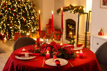 Stylish Christmas table setting with plates, festive decor and burning candles indoors