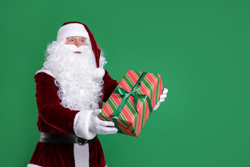 Santa Claus with Christmas gift on green background, space for text